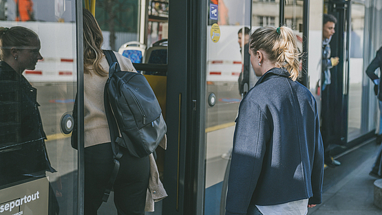 Passantinnen und Passanten die an einem sonnigen Tag an einer Haltestelle in einen Trolleybus der Verkehrsbetriebe Luzern AG einsteigen.